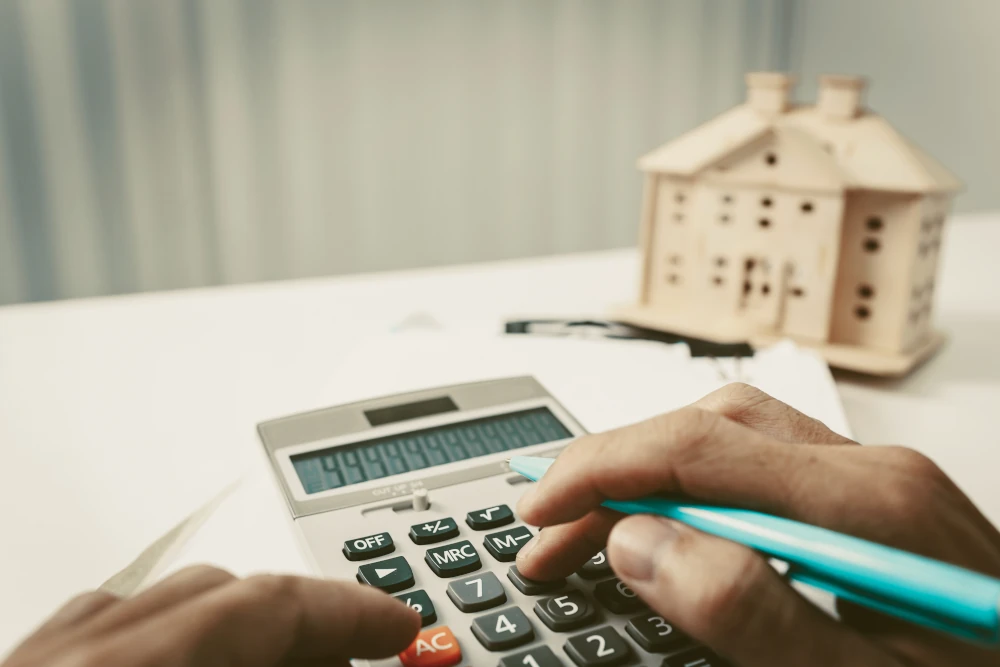 Homem calculando os custos das finanças na calculadora visando evitar a penhora de imóvel por dívida de condomínio.