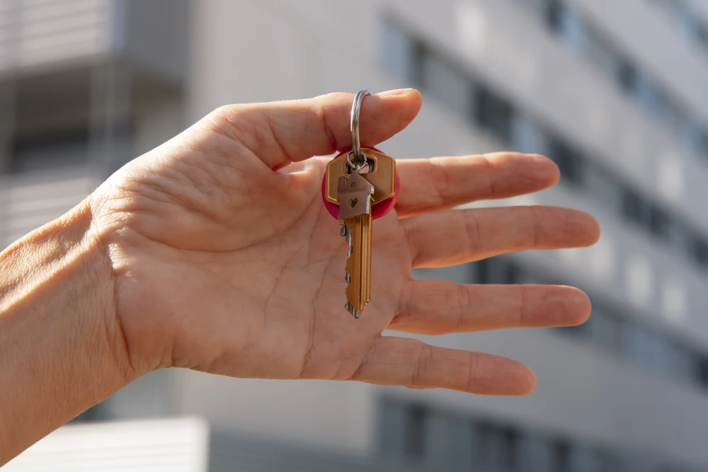 Uma mão segurando as chaves de uma casa ao ar livre, representando a libertação de poder quitar as dívidas condominiais por meio de um acordo extrajudicial.