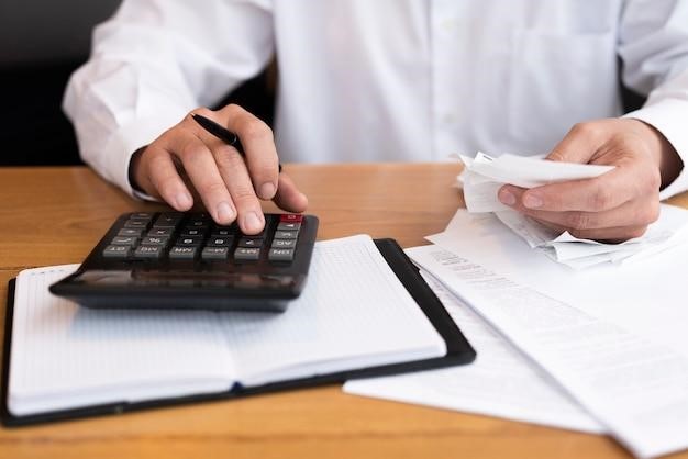 Homem fazendo as contas da sua dívida condominial em uma calculadora.