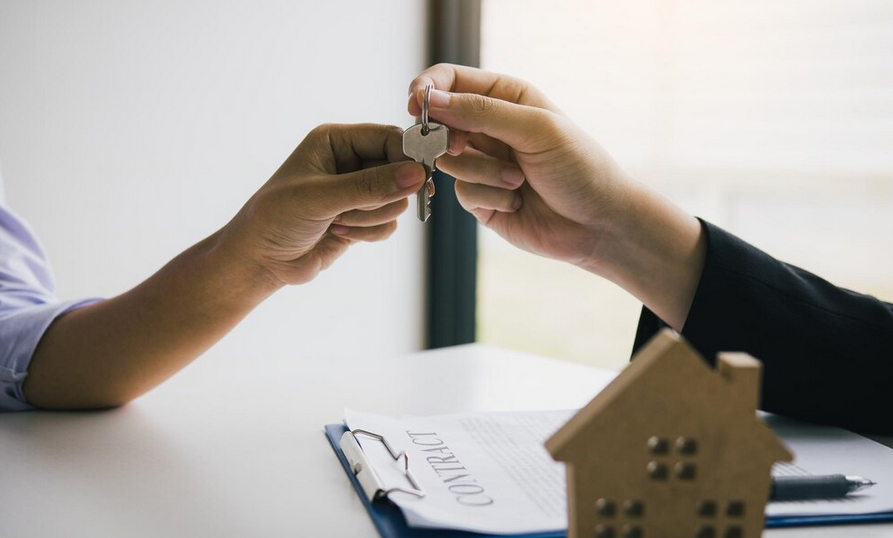 Mão de um credor passando a chave para o proprietário, representando a importância de estratégias para evitar leilão de dívida condominial