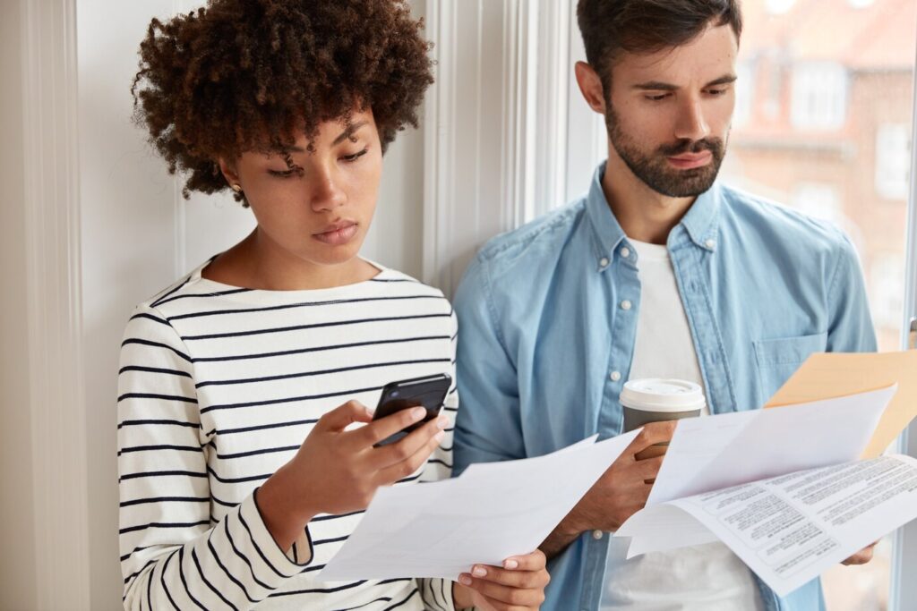 Jovem casal recebendo um documento de notificação de leilão de imóvel.