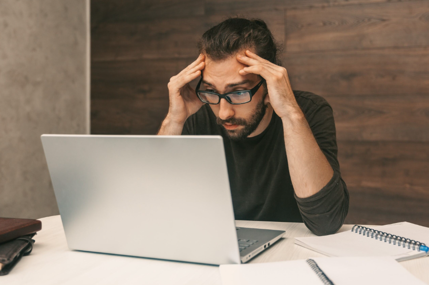 Homem olhando preocupado para um notebook após analisar os valore bloqueados pela penhora online.