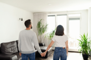 Casal de mãos dadas na sala de casa, com medo da penhora do imóvel.