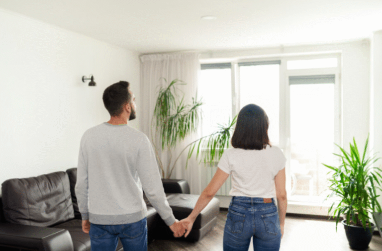 Casal de mãos dadas na sala de casa, com medo da penhora do imóvel.